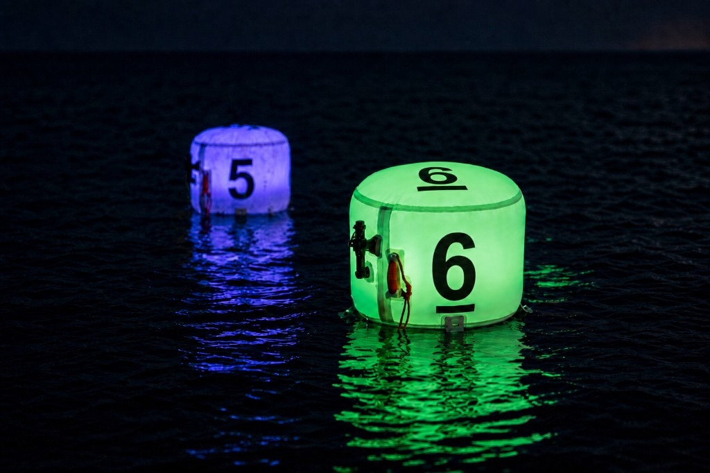 Two XP FROQ marking buoys on water at night: green buoy with number 6 and purple buoy with number 5
