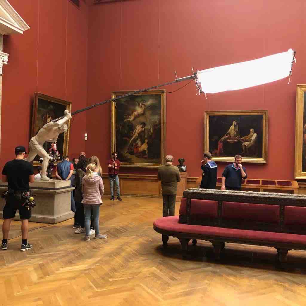 Dreh in einem Museumssaal; eine Carpetlight hängt an einem Ausleger über der Szene